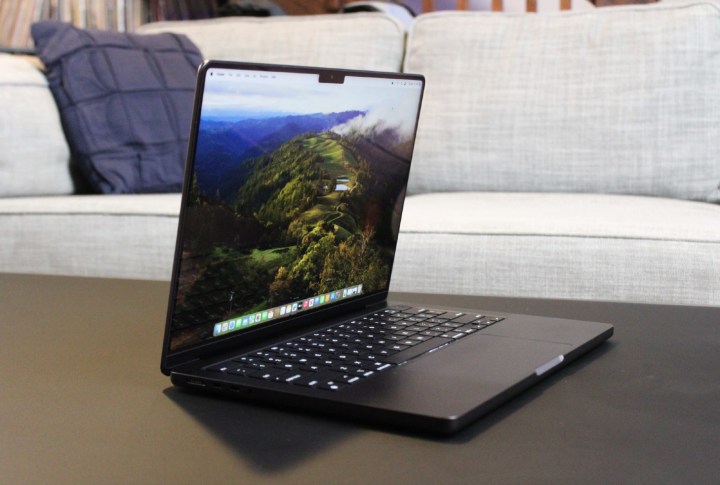 The MacBook Pro open on a table in front of a couch.