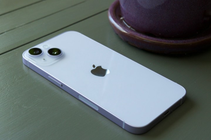 An iPhone 14 laying face-down on a table.