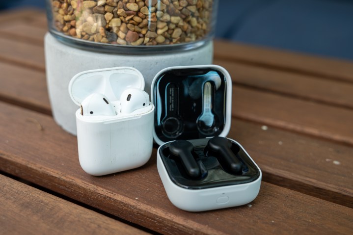 Some old Apple AirPods in their case, alongside the new 2023 Amazon Echo Buds.