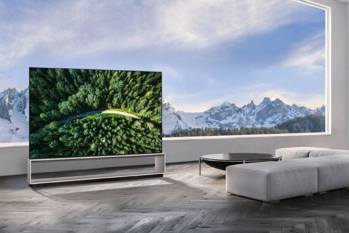 An LG 8K OLED TV in a living room with a mountainous scene in the background. 