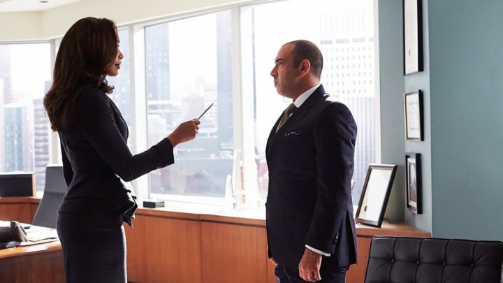 Jessica handing Louis a pen in her office in a scene from Suits.