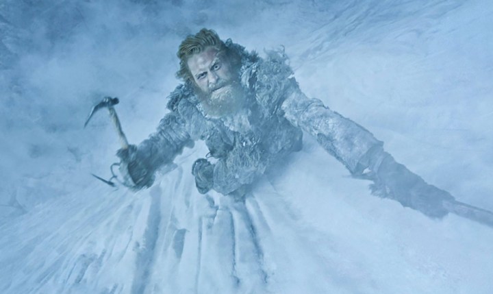 A man scales an ice wall with a pick in Game of Thrones.
