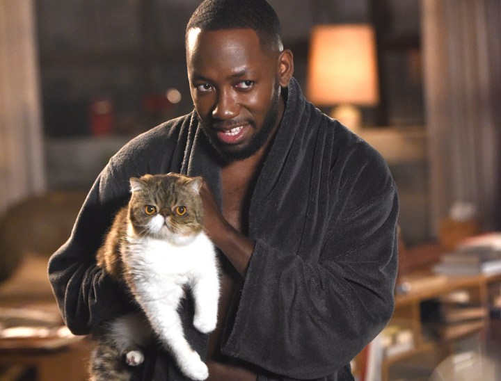 Winston holds his cat in the loft in New Girl