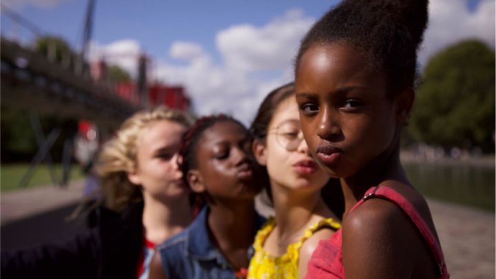 Three young girls blow kisses with their eyes closed while a fourth girl looks at the camera in the 2020 movie Cuties.