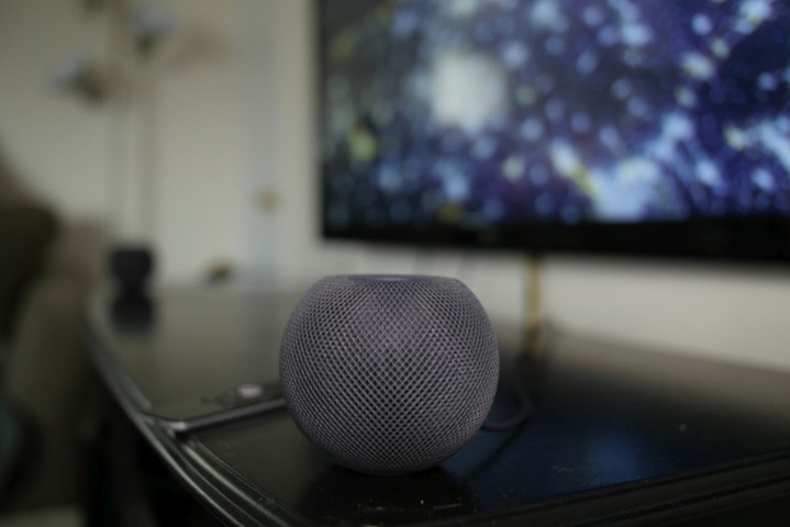An Apple HomePod Mini sits on top of entertainment center.