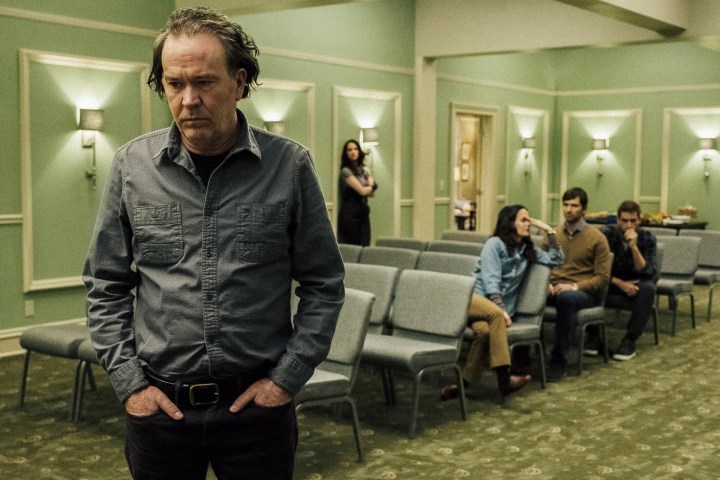 Hugh stands near his family in The Haunting of Hill House.