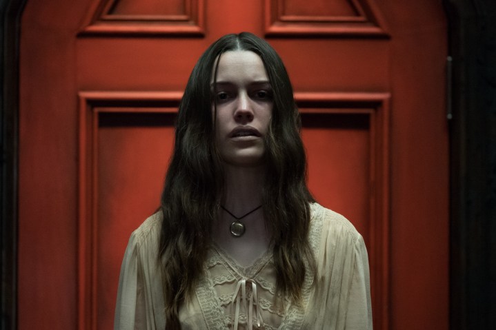 Nell stands by a red door in The Haunting of Hill House.