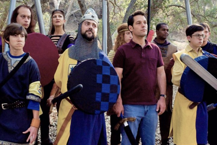 A group of men stand next to each other dressed up in costume with swords.