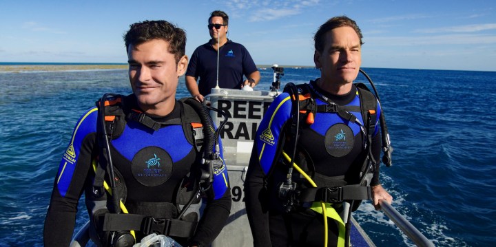 Two men prepare to scuba dive in Down to Earth with Zac Efron.