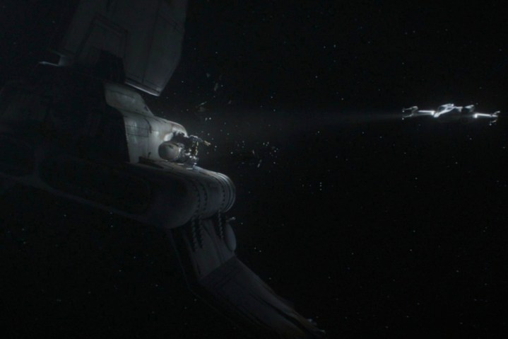 An X-Wing shines a light on a destroyed Imperial prisoner transport ship in The Mandalorian season 3 episode 5.