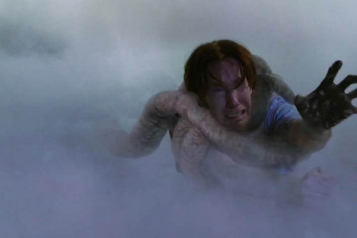A character from The Mist is being pulled into a misty background by a creature's tentacle.