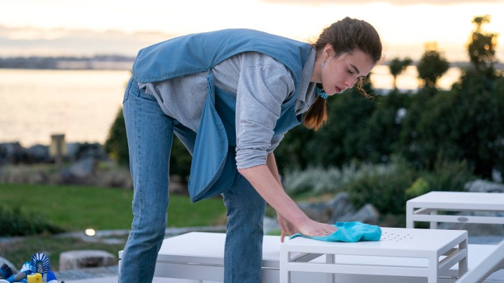 A woman in a maid's uniform scrubbing a surface in the Netflix series Maid.