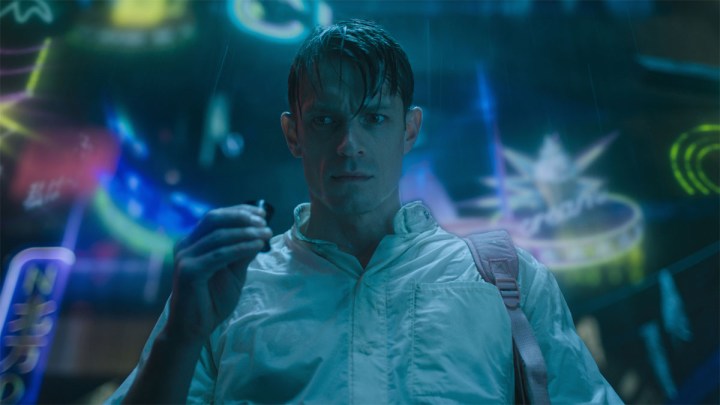 Joel Kinnaman sits in a chair and touches light in Altered Carbon.