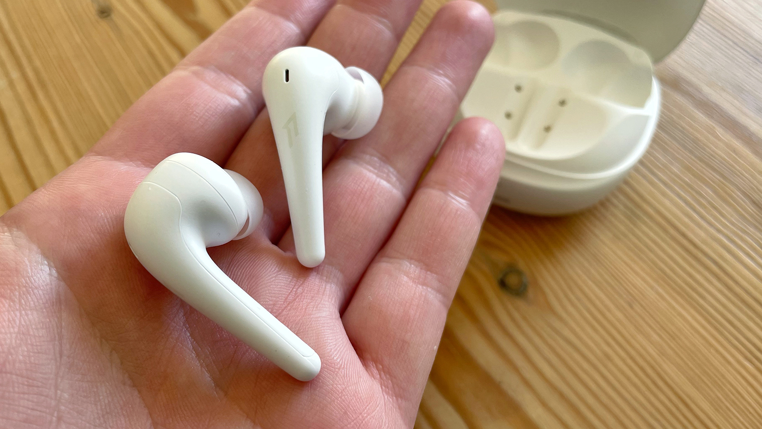 The 1More Aero true wireless earbuds pictured in the palm of someone's hand.