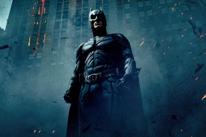 Batman stands in a cloud of ash and rubble in a poster for The Dark Knight.