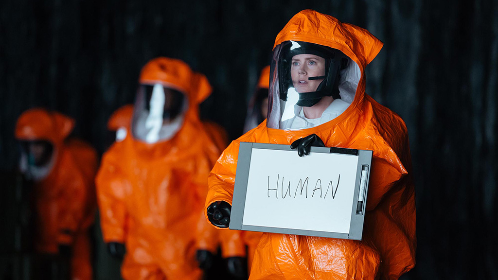 A still from the movie Arrival in which Amy Adams holds up a sign that says human.