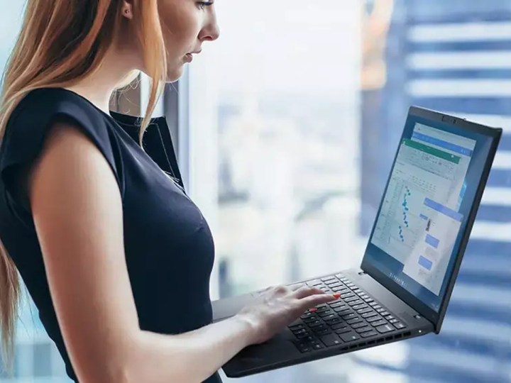 A person holding a ThinkPad Nano X1 Gen 2 laptop in front of a window.