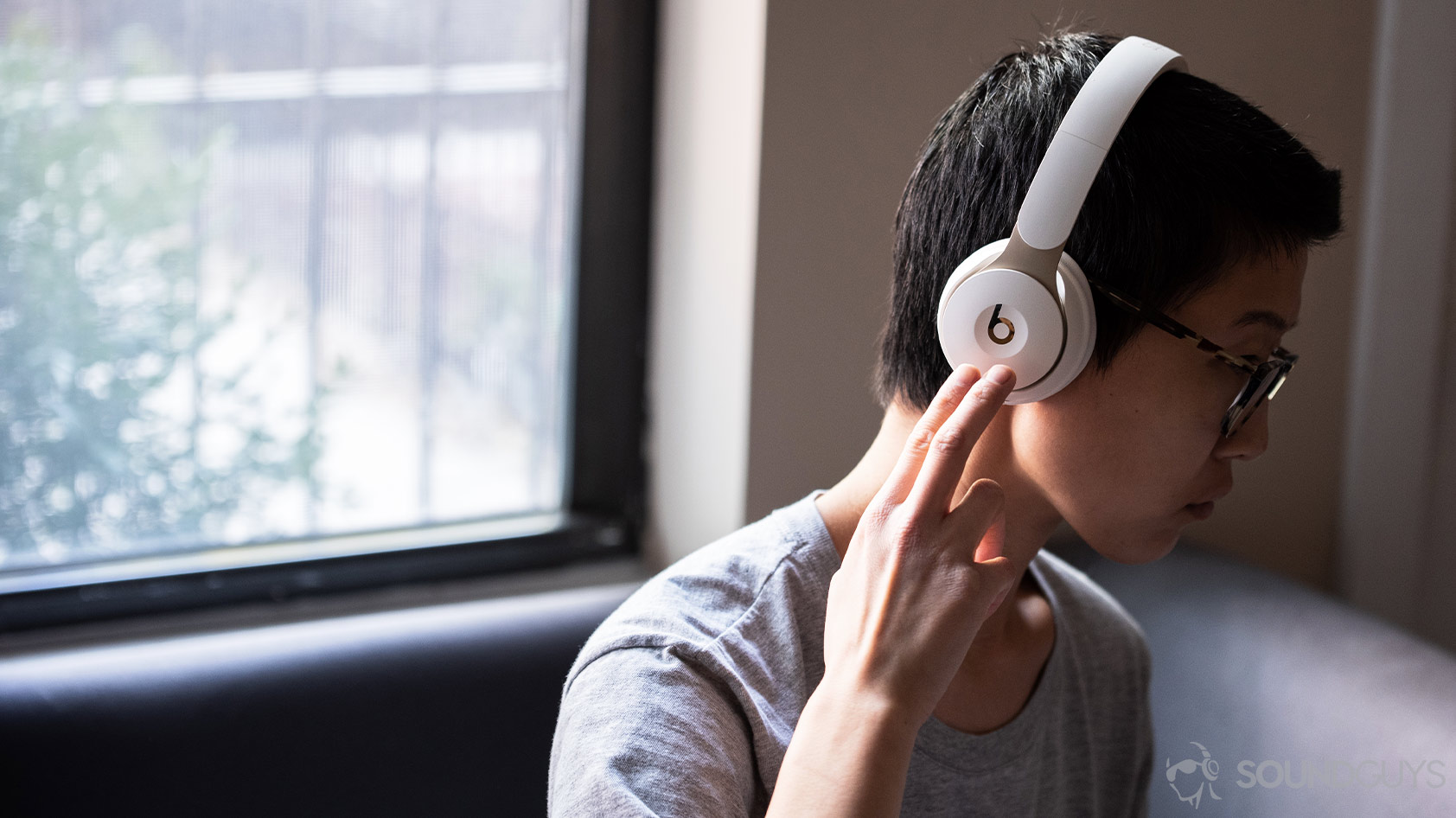 A photo of the Beats Solo Pro on-ear noise canceling headphones being worn by a woman using the right ear cup controls.