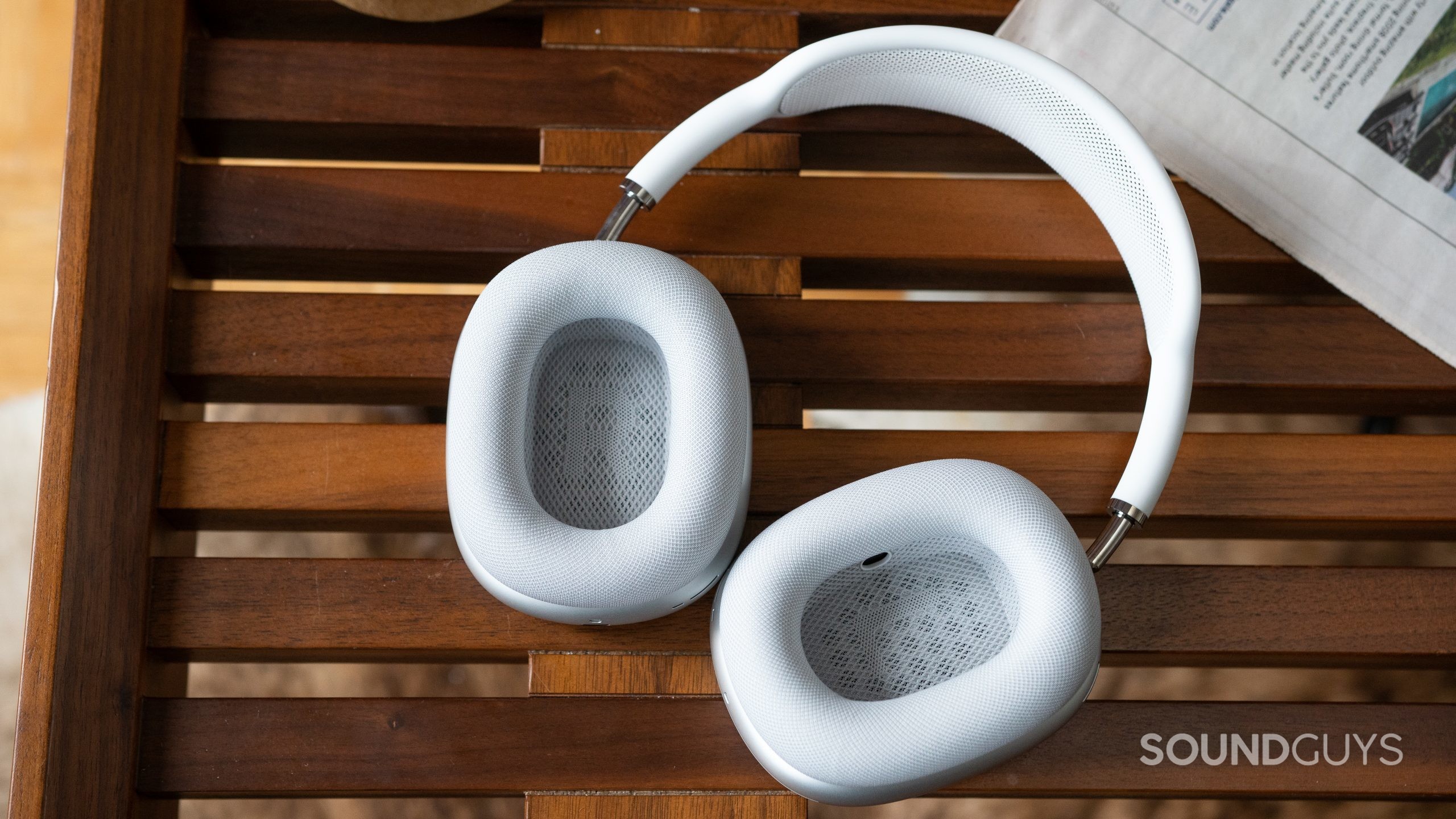 The white Apple AirPods Max lying flat so you can see inside the ear cups as they rest on a coffee table.