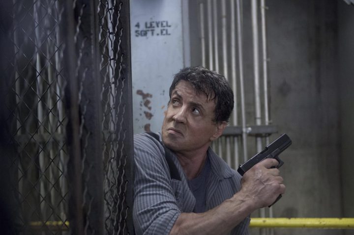 Sylvester Stallone holding a gun on a fence in Escape Plan.