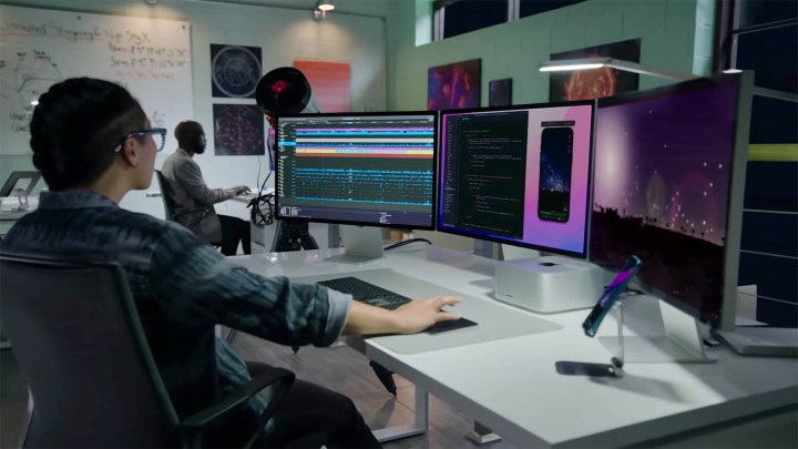 A person works at a station equipped with the all new Mac Studio and Studio Display.