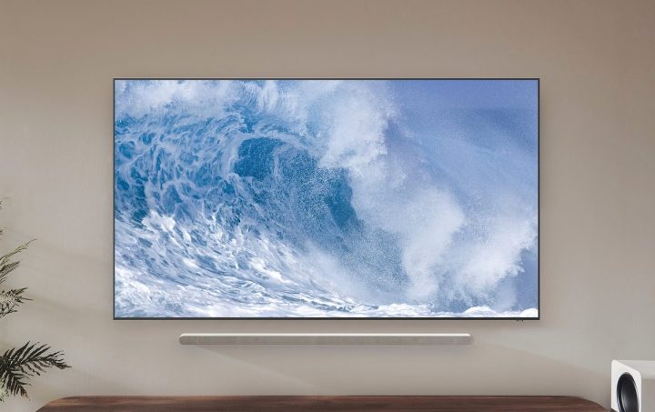 The Samsung QN700B QLED 8K TV with a wave on the screen, while mounted to a wall.