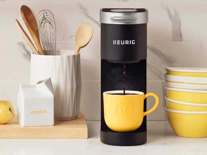 Keurig coffee maker K-Mini on a kitchen counter with lemon-colored cup and bowls.
