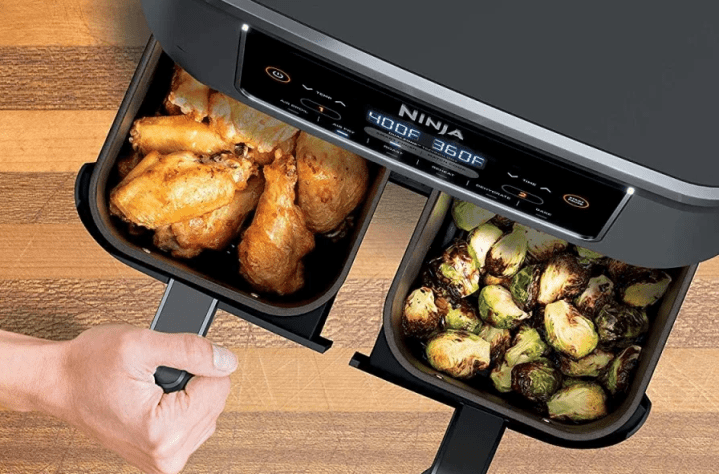 Ninja Foodi two-basket air fryer with chicken wings in left basket and brussel sprouts in right basket.