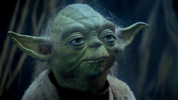 Yoda standing in front of a dark background.